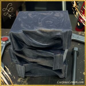 Stack of artisan soap bars called “Mechanic Hands” by Luxious Lemon, featuring rugged swirls and a matte finish. Made with organic pumpkin seed oil, orange essential oil, charcoal, and exfoliating red sandalwood powder—perfect for hardworking hands like mechanics or gardeners.